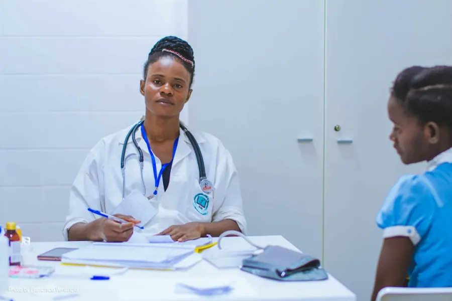 African doctor in a white coat with a young patient, medical travel from Uganda