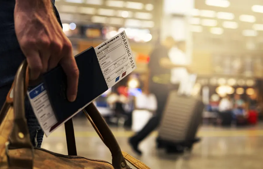 Traveller holding a passport and boarding pass at the airport, student travel from Uganda